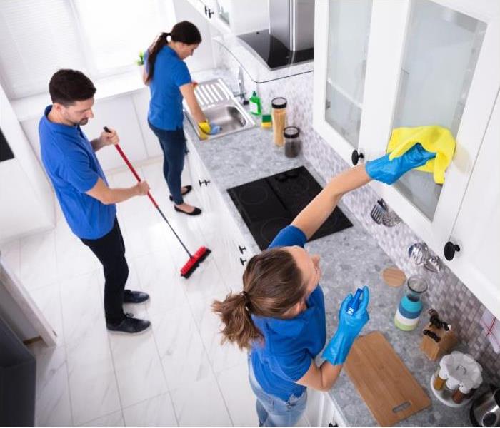 A cleaning team doing their job in the kitchen of a home.