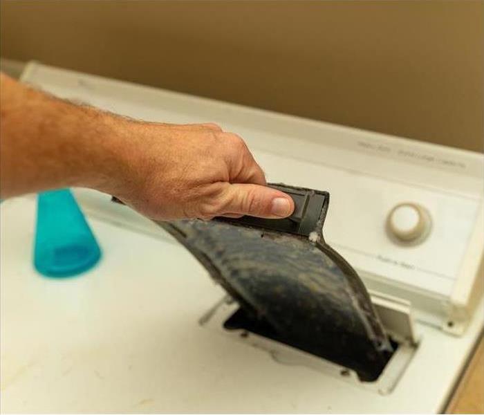 A person removing lint from the dryer