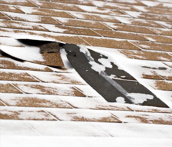 Image of a damaged roof with snow. 